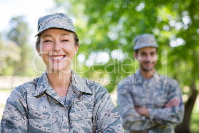 Portrait of a military couple standing with arms crossed in park