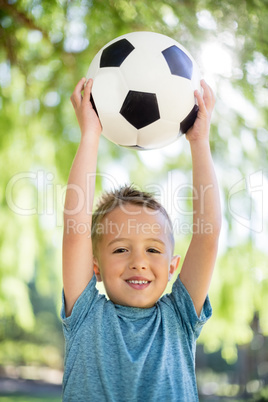 Portrait of boy holding a football in park