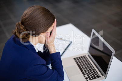 Tired businesswoman sitting at desk with laptop