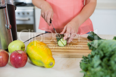 Woman cutting a cucumber on chopping board