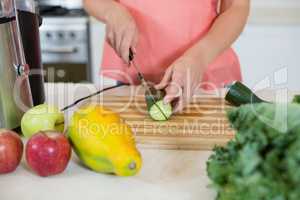 Woman cutting a cucumber on chopping board