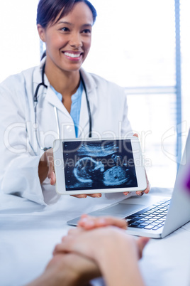 Doctor showing babies ultrasound scan on digital tablet