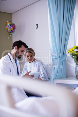 Male doctor interacting with female senior patient in the ward