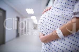 Mid section of pregnant woman standing in corridor
