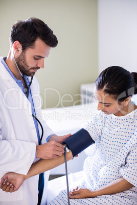 Male doctor checking blood pressure of a female patient