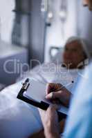 Male doctor writing a prescription on a clipboard