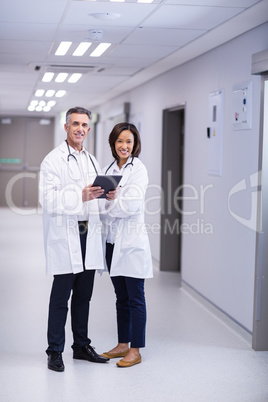 Portrait of doctors using digital tablet in corridor