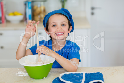 Smiling boy mixing cookie dough in kitchen