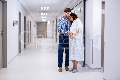 Man comforting pregnant woman in corridor