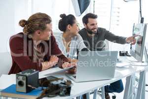 Team of photographers working over computer at desk