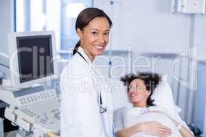 Portrait of smiling doctor doing ultrasound scan for pregnant woman