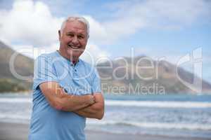 Portrait of senior man standing with arms crossed on the beach