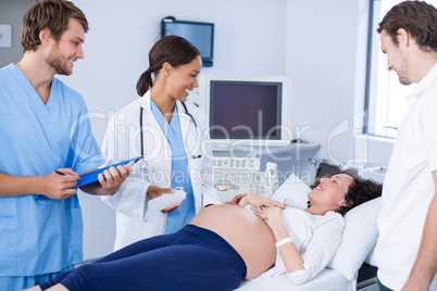 Doctor interacting with pregnant woman while doing ultrasound scan