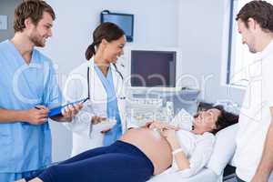 Doctor interacting with pregnant woman while doing ultrasound scan