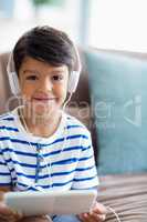 Boy listening music on digital tablet in living room at home