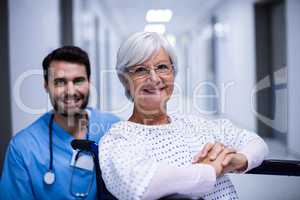 Portrait of male doctor and female senior patient smiling in the corridor