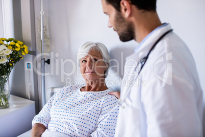 Male doctor consoling female senior patient