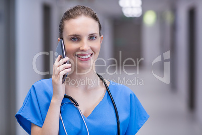 Portrait of female doctor talking on mobile phone in corridor