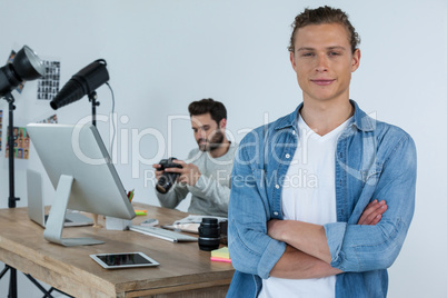 Smiling photographer standing with his arms crossed in studio