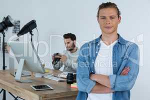 Smiling photographer standing with his arms crossed in studio