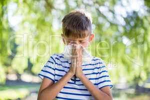 Boy wiping his nose while sneezing