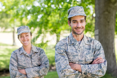 Portrait of a military couple standing with arms crossed in park