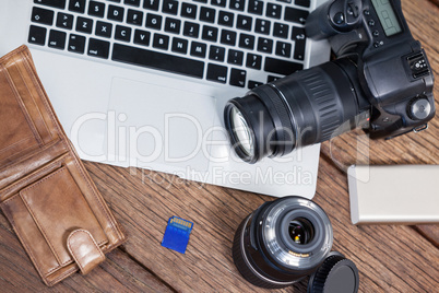 Close-up of digital camera, lens, memory card, laptop on table