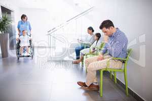 Man sitting on chair in hospital corridor