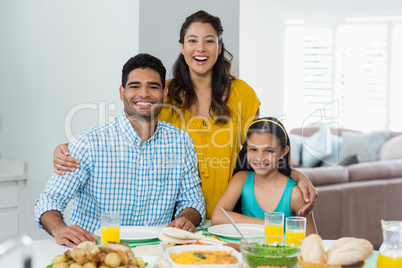 Daughter and parents having meal on table at home