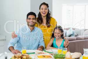 Daughter and parents having meal on table at home