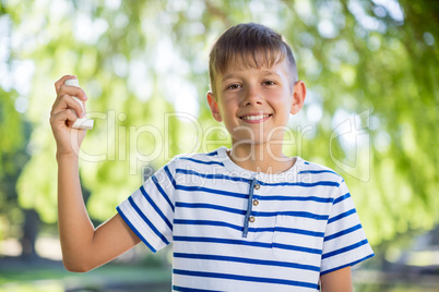 Boy holding asthma inhaler in park
