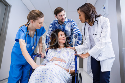 Doctors and man comforting pregnant woman in corridor