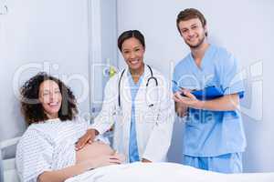 Portrait of doctors examining pregnant woman in ward
