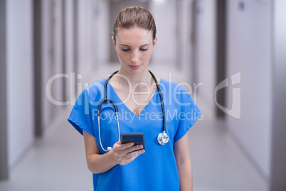 Female doctor using mobile phone in corridor