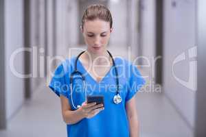 Female doctor using mobile phone in corridor