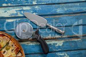 Italian pizza served on pizza tray with cutter and knife on wooden plank