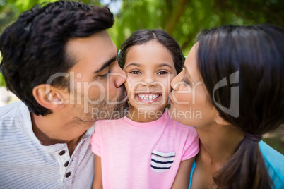Girl being kissed by his parents in park