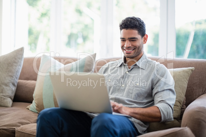 Man sitting on sofa and using laptop in living room