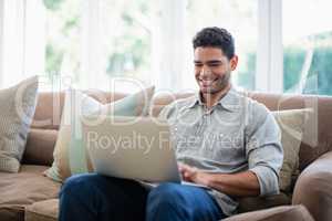 Man sitting on sofa and using laptop in living room