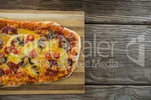 Italian pizza served on chopping board on a wooden plank