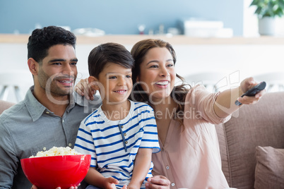 Parents and son watching television in living room