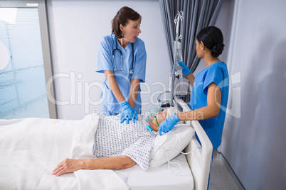 Doctor and nurse treating senior patient in ward