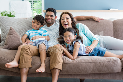 Happy parents and kids sitting on sofa in living room