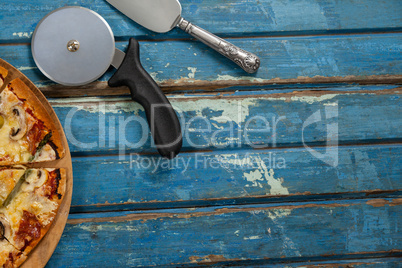 italian pizza served on pizza tray with cutter and knife on wooden plank