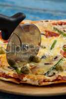 Delicious pizza served on pizza tray with cutter on pizza