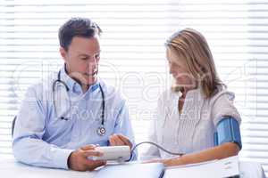 Doctor checking blood pressure of a patient in clinic