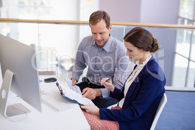 Businesswoman working at desk with colleague