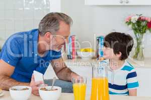 Happy father interacting with son while having breakfast in kitchen