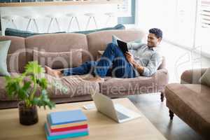 Man sitting on sofa and using digital tablet in living room