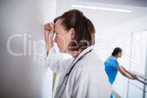 Depressed doctor leaning against wall